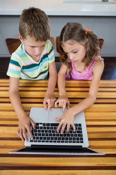 Irmãos usando laptop na cozinha — Fotografia de Stock