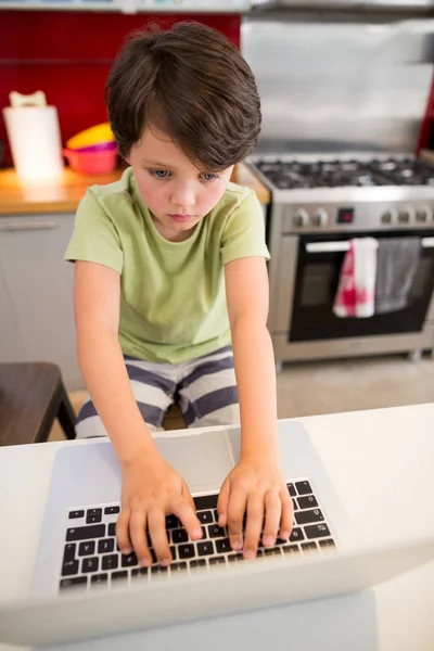 Boy pomocí přenosného počítače v kuchyni — Stock fotografie