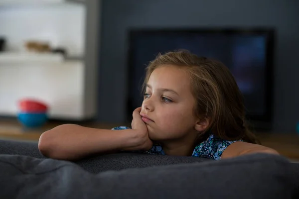 Расстроенная девушка сидит на диване в гостиной — стоковое фото