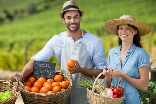 Man and woman standing by fresh vegetables — Stock Photo, Image