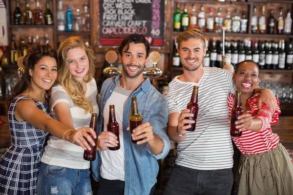 Amigos alegres segurando garrafas de cerveja no pub — Fotografia de Stock