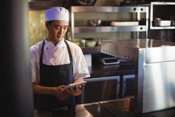 Шеф-повар с помощью цифрового планшета на кухне — стоковое фото
