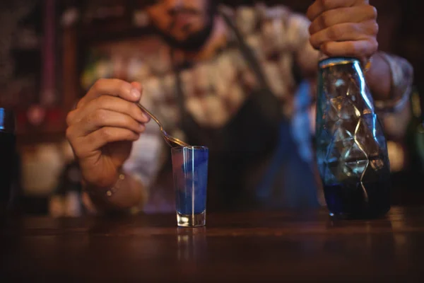 Garçom derramando bebida cocktail em copos de tiro — Fotografia de Stock