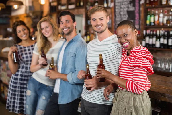 Amigos alegres con botellas de cerveza en el pub — Foto de Stock