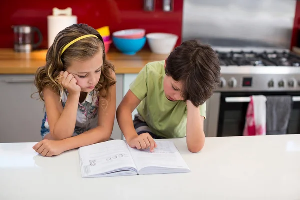 Livre de lecture des frères et sœurs dans la cuisine — Photo