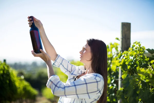 Vrouw met fles wijn bij wijngaard — Stockfoto