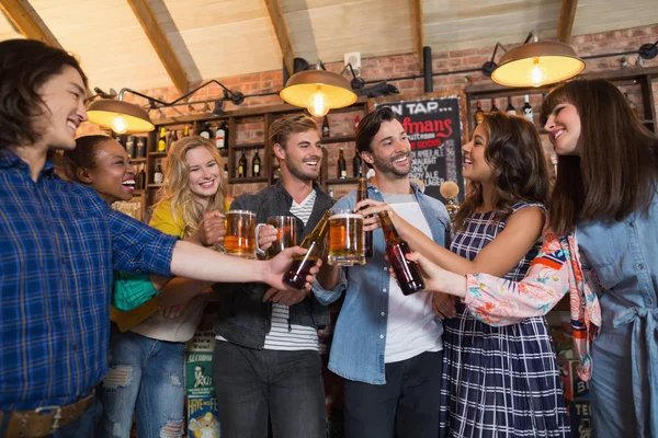 Friends toasting beer glasses and bottles in pub — Stock Photo, Image
