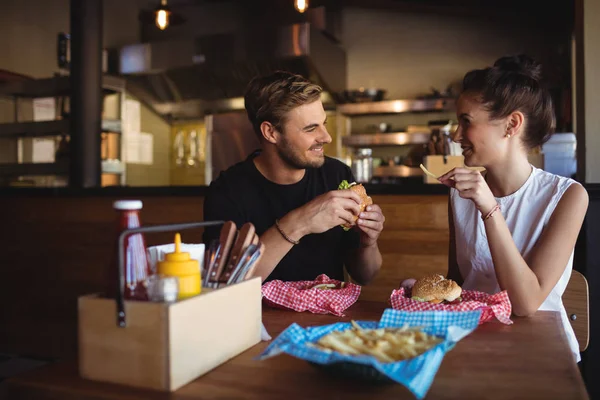 Pareja interactuando mientras comida rápida — Foto de Stock