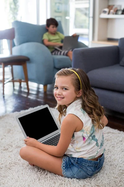 Leende flicka använder laptop i vardagsrum — Stockfoto