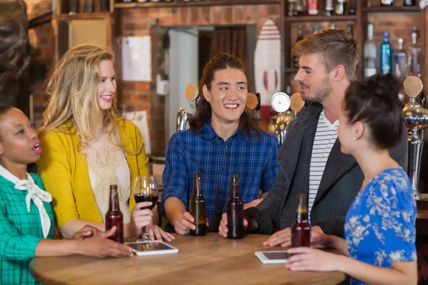 Vrienden praten terwijl je door tabletten en bier — Stockfoto