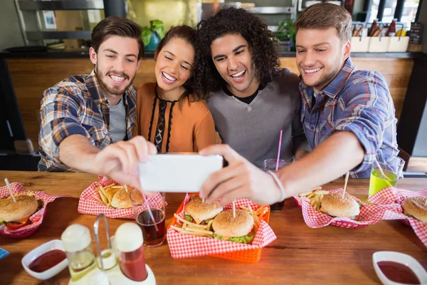 Amigos alegres tomando selfie no restaurante — Fotografia de Stock
