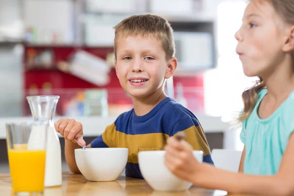 Sibling having breakfast cereal in kitchen — Stock Photo, Image