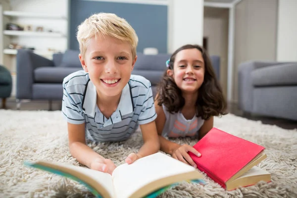 Rodzeństwo, leżąc na dywanie i czytanie książki — Zdjęcie stockowe