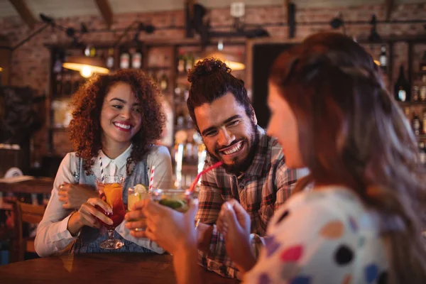 Amigos interactuando entre sí tomando bebidas — Foto de Stock