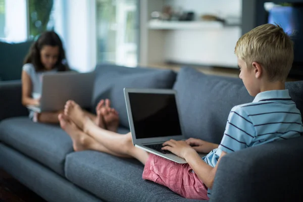 Frères et sœurs utilisant un ordinateur portable dans le salon — Photo