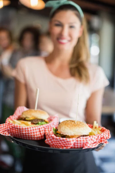 Garçonete servindo hambúrgueres no restaurante — Fotografia de Stock