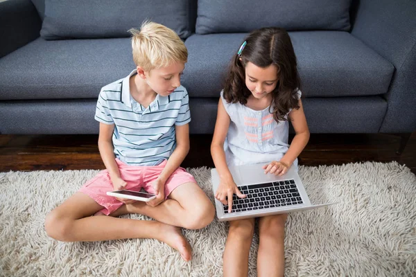 Siblings using tablet and laptop — Stock Photo, Image