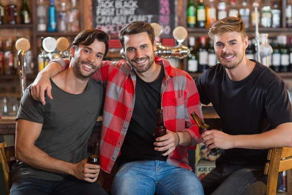 Amigos varones sosteniendo botellas de cerveza en el bar —  Fotos de Stock