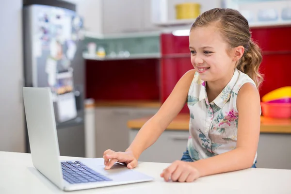 Leende flicka använder laptop i köket — Stockfoto