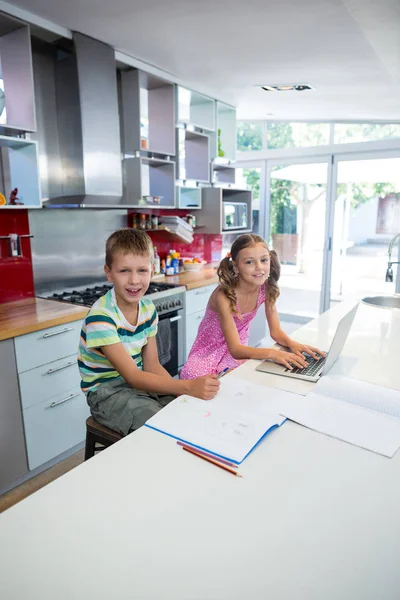 Hermanos haciendo sus deberes en la cocina — Foto de Stock