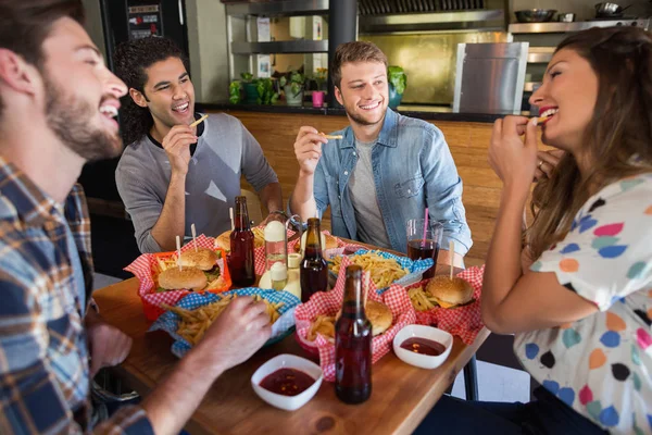 Amigos alegres comendo batatas fritas — Fotografia de Stock