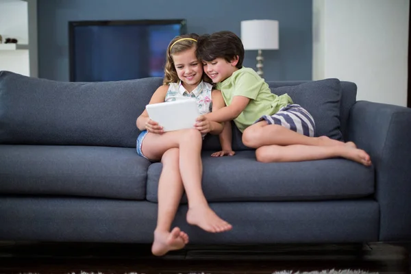 Siblings using digital tablet in living room — Stock Photo, Image