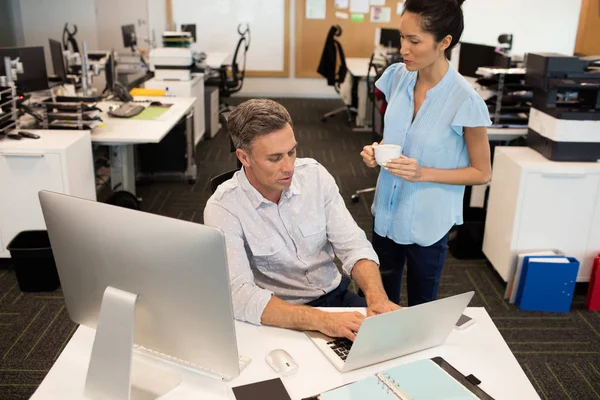 Businesswoman standing by male colleague in office — Stock Photo, Image