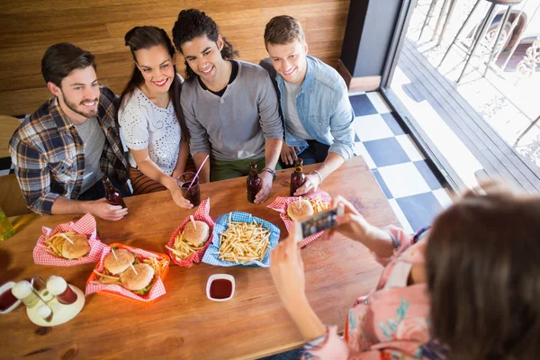 Vrouw fotograferen vrienden in restaurant — Stockfoto