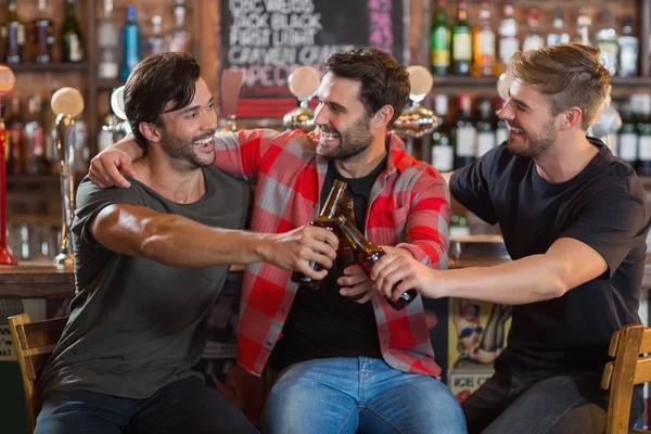 Amigos do sexo masculino brindar garrafas de cerveja no bar — Fotografia de Stock