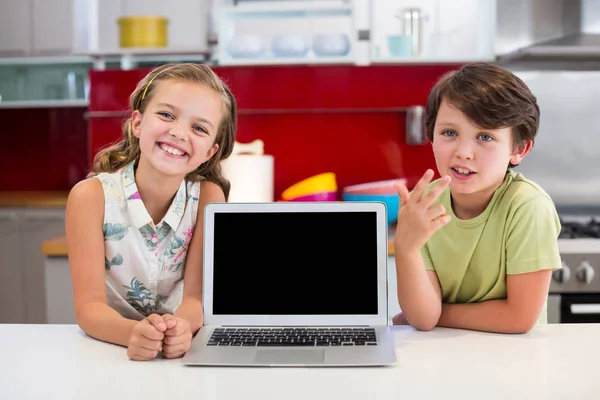 Broers en zussen met laptop op aanrecht in de keuken — Stockfoto
