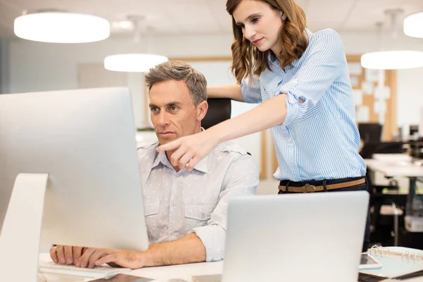 Female colleague assisting businessman working — Stock Photo, Image