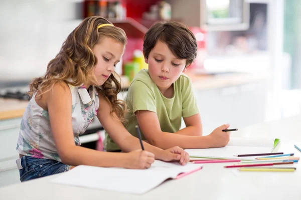 Siblings doing homework in kitchen — Stock Photo, Image