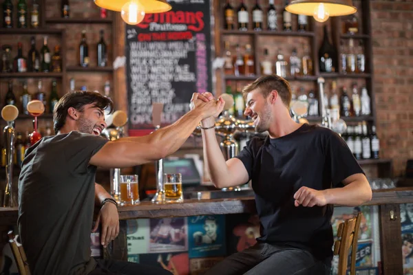 Masculino amigos dando alta cinco enquanto sentado no bar — Fotografia de Stock