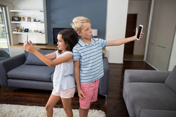 Broers en zussen selfie te nemen op hun telefoon in woonkamer — Stockfoto