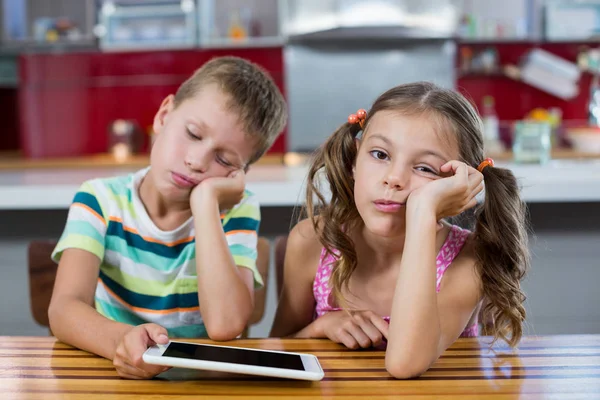 Gelangweilte Geschwister mit digitalem Tablet in der Küche — Stockfoto