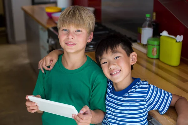 Frères et sœurs souriants utilisant une tablette numérique dans la cuisine — Photo