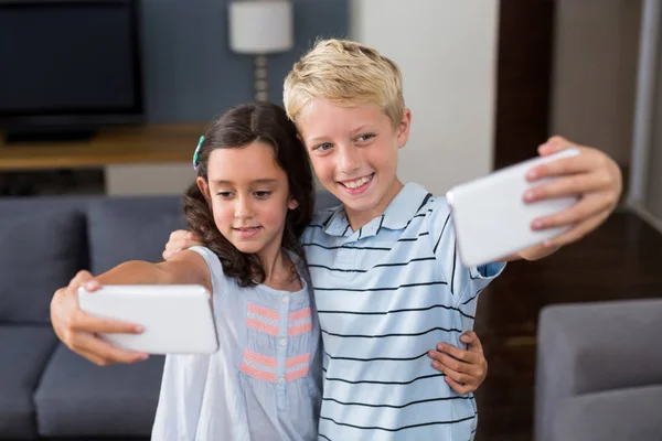 Frères et sœurs prenant selfie au téléphone dans le salon — Photo