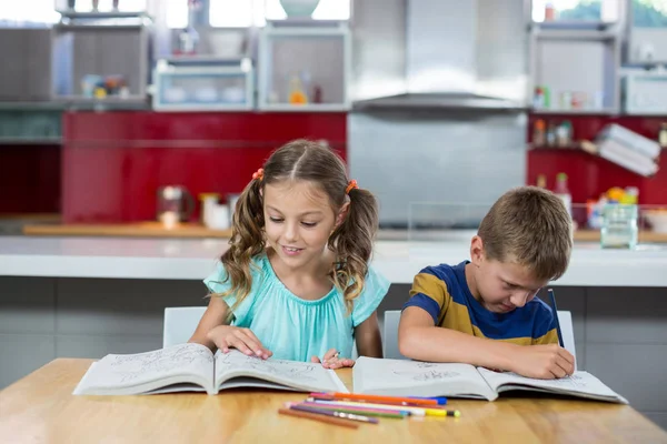 Frères et sœurs faisant leurs devoirs dans la cuisine — Photo