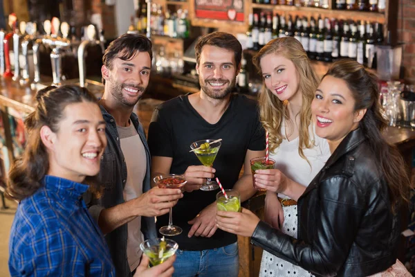 Friends holding drinks while standing in bar — Stock Photo, Image