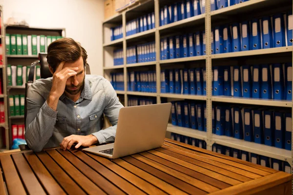 Verkrampte zakenman met behulp van laptop — Stockfoto