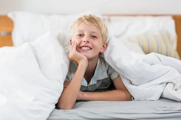 Boy lying under bed sheet in bedroom — Stock Photo, Image