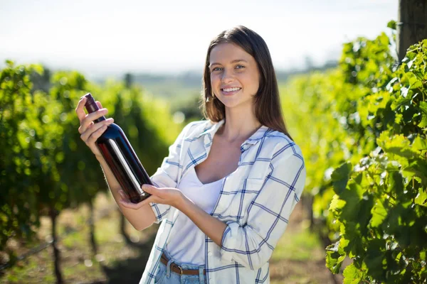 Mulher segurando garrafa de vinho na vinha — Fotografia de Stock
