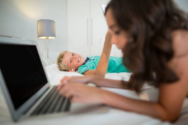 Hermanos usando tableta digital y portátil en la cama — Foto de Stock