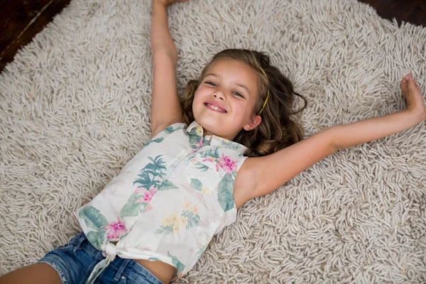 Lächelndes Mädchen liegt auf Teppich im Wohnzimmer — Stockfoto