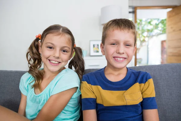 Siblings sitting together on sofa in living room — Stock Photo, Image