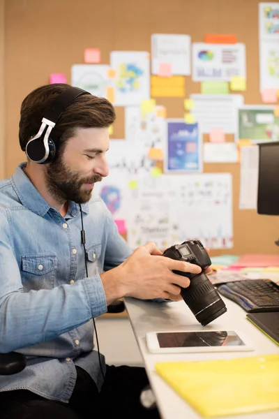Photographer wearing headphones while using camera — Stock Photo, Image