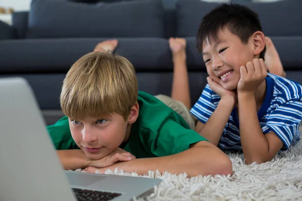 Geschwister liegen auf Teppich und benutzen Laptop — Stockfoto