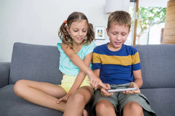 Fratelli e sorelle che utilizzano tablet sul divano in soggiorno — Foto Stock