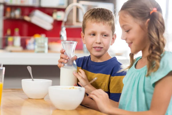 Sibling having breakfast cereal in kitchen — Stock Photo, Image