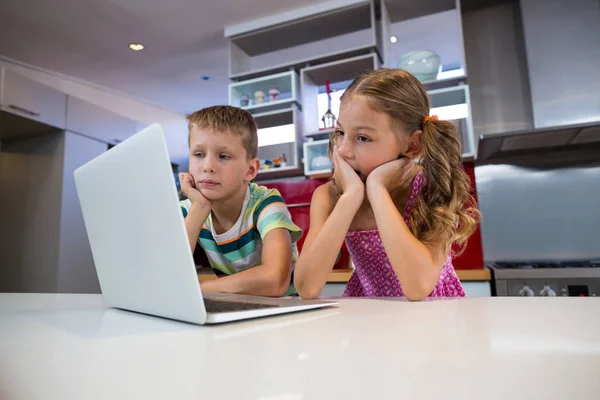 Siblings using laptop in kitchen — Stock Photo, Image